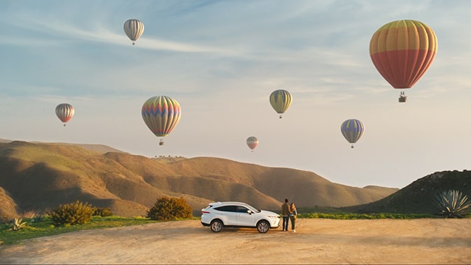 Image of vehicle with hot-air balloons in the sky with no text.