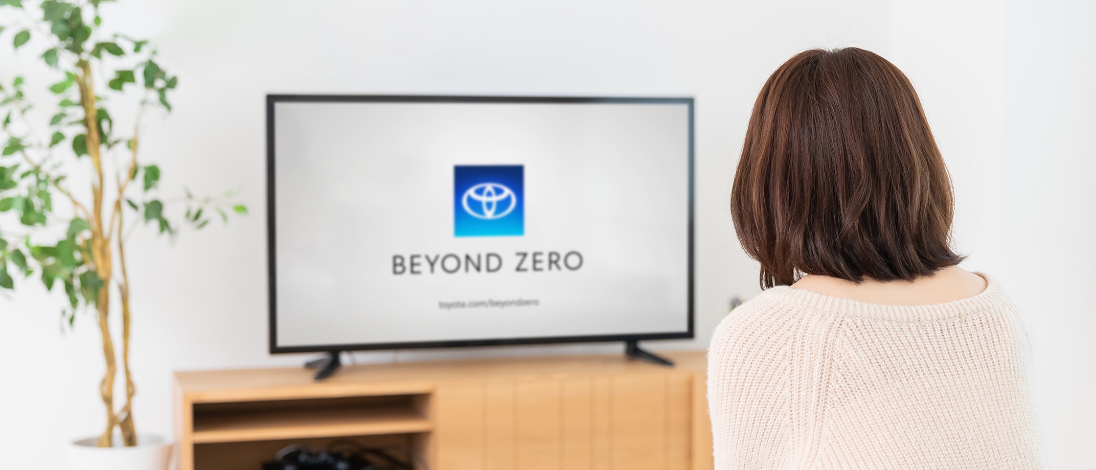 A woman sitting in front of a TV with the Beyond Zero logo displayed on the screen.