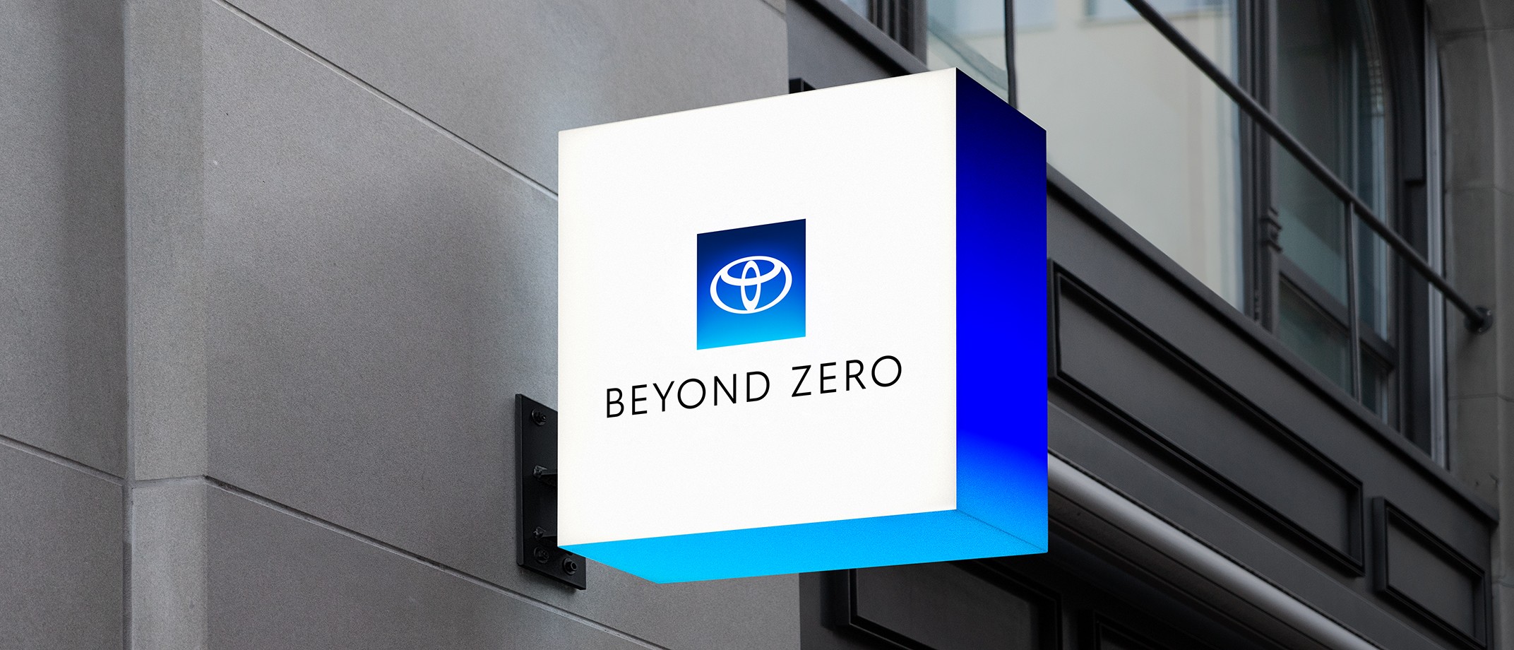 A lit up sign on a building with Beyond Zero logo and gradient.