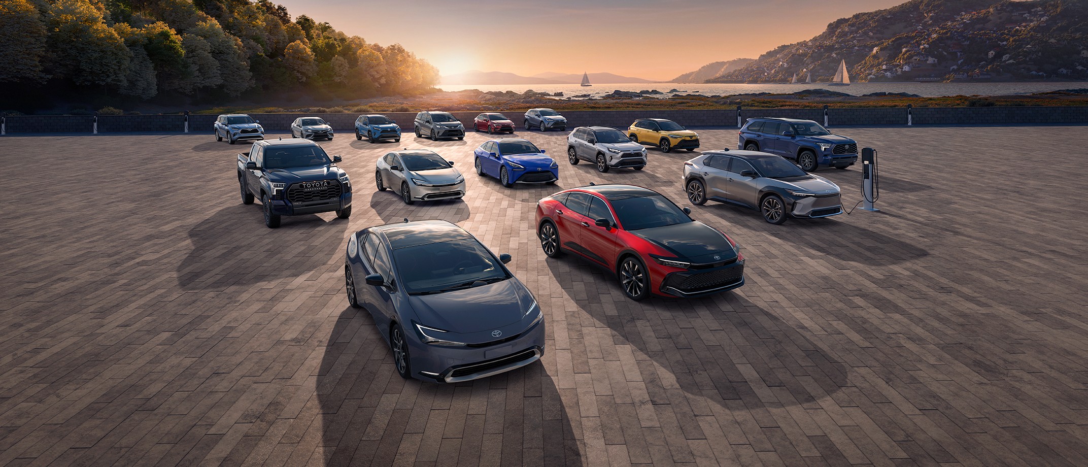 Overhead Image of the electrified vehicle lineup parked in front an ocean sunset background.