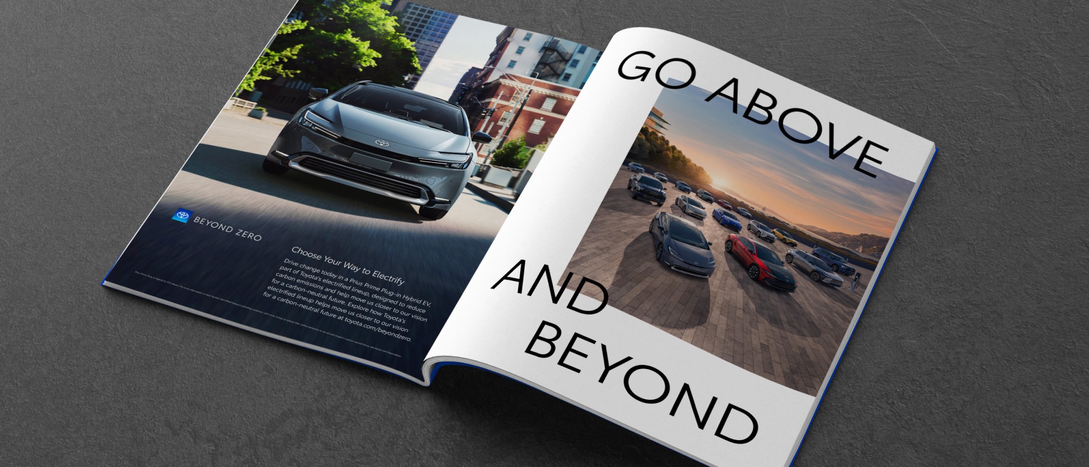 An open magazine against a dark grey background. The open pages of the magazine display a Toyota ad featuring the lineup of Electrified Vehicles, body text, the Beyond Zero logo and a headline that reads “Go Above and Beyond.”