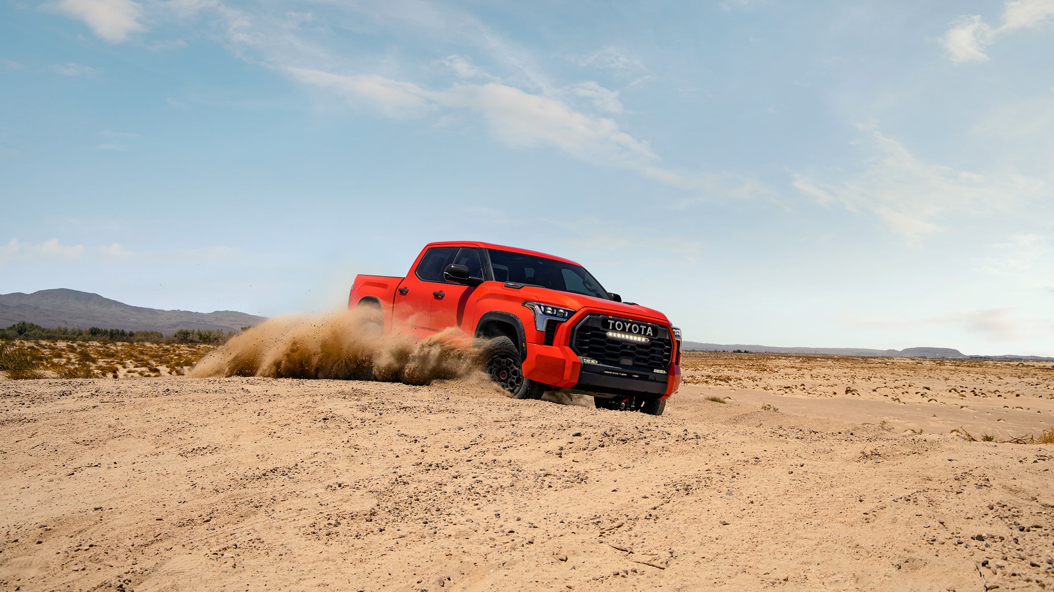 The Tundra TRD Pro kicks up dirt in the desert. A slider divides the image in half, showing what it looks like when color profile is added to the image.