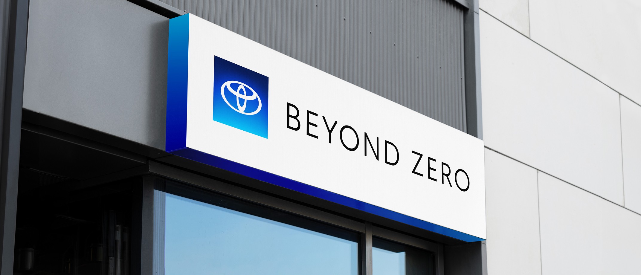 A lit up sign on a building showing the Beyond Zero logo and gradient.
