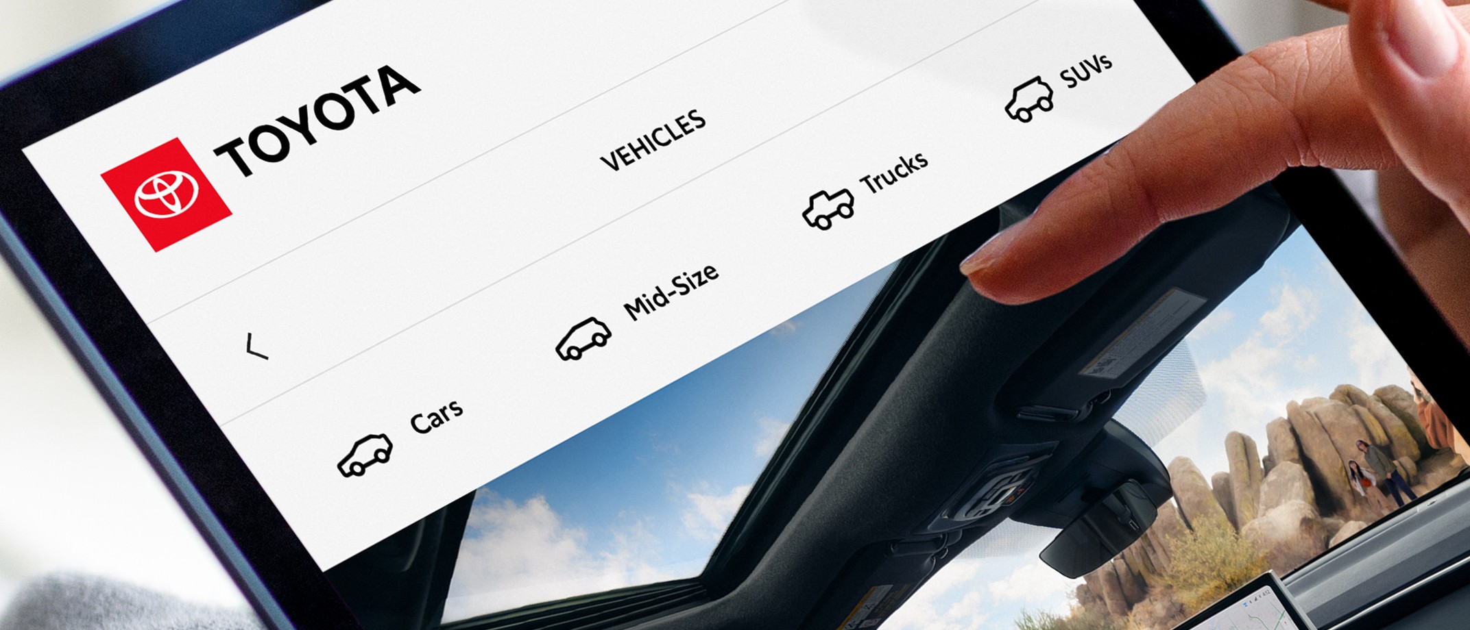 A hand hovers above a tablet screen showing a Toyota webpage with different vehicle icons for “Cars,” “Mid-Size,” “Trucks” and “SUVs.”