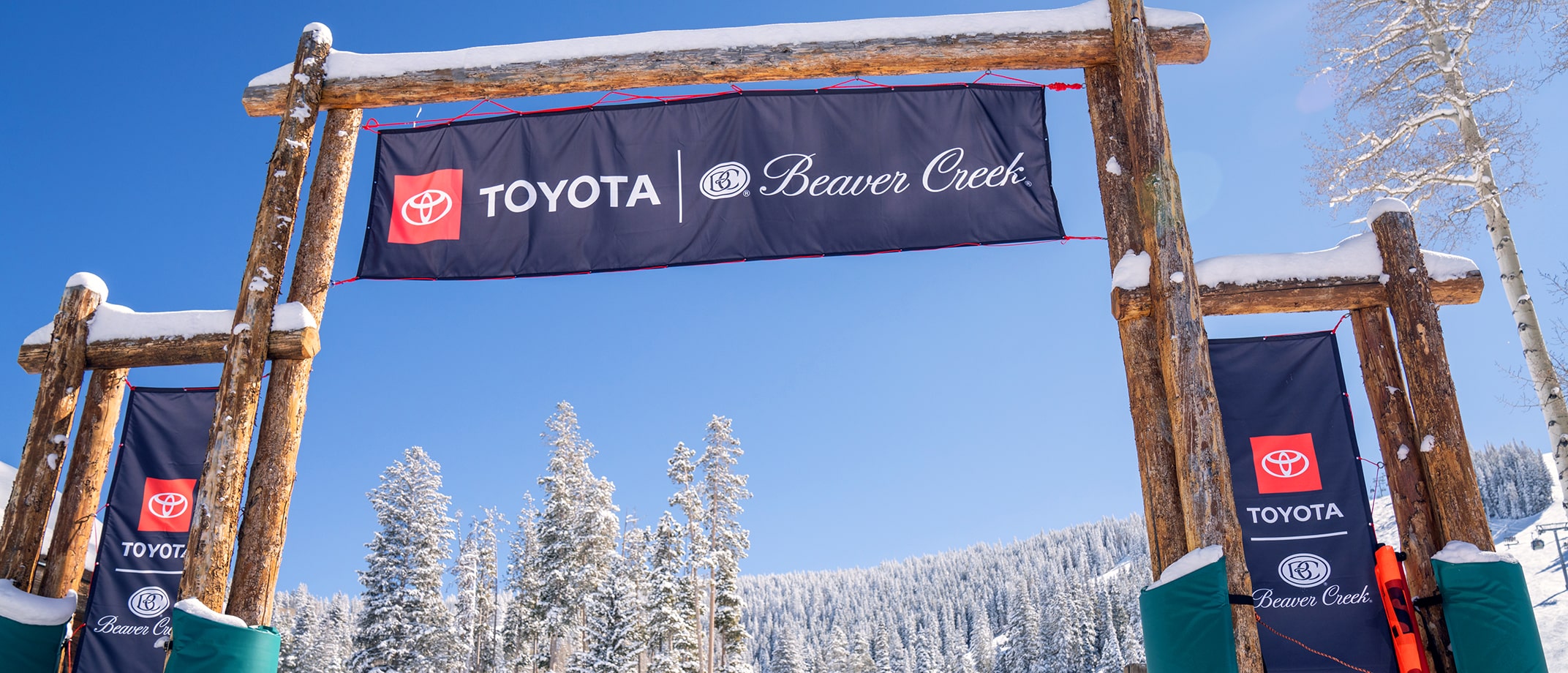Three banner ads with a lockup of the Toyota logo and Beaver Creek resort’s logo hang on display at the entrance of a ski resort.