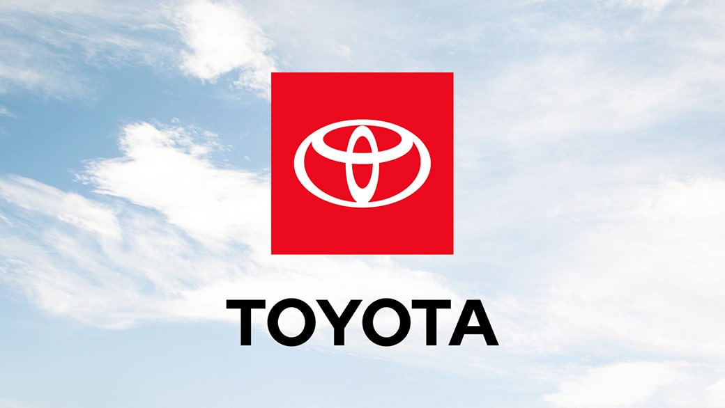 The full-color Toyota logo is displayed against a blue sky with white clouds.