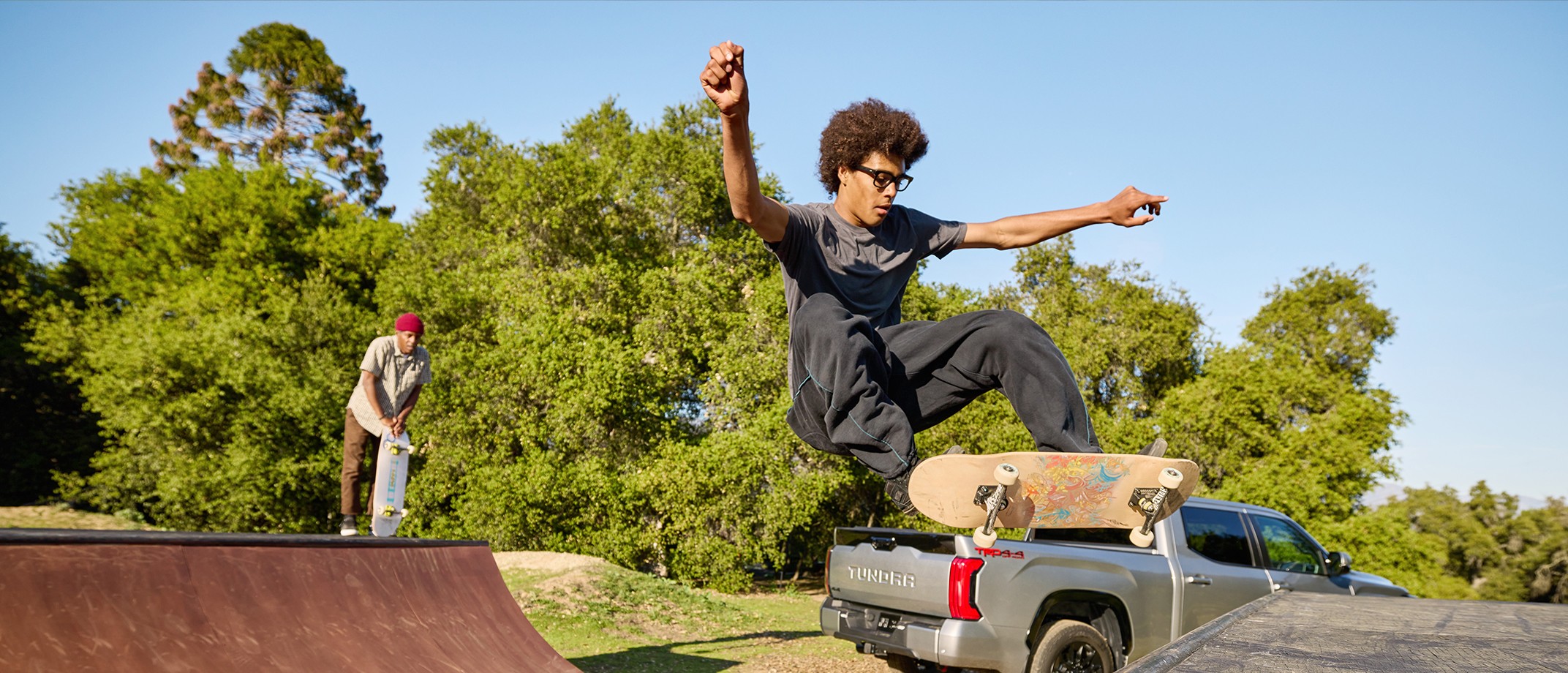 Air shot of guy on skateboard with another man standing on skate ramp watching