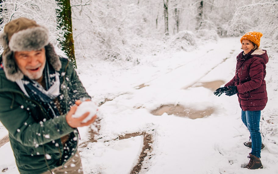 A father and daughter having a snowball fight in a winter landscape.