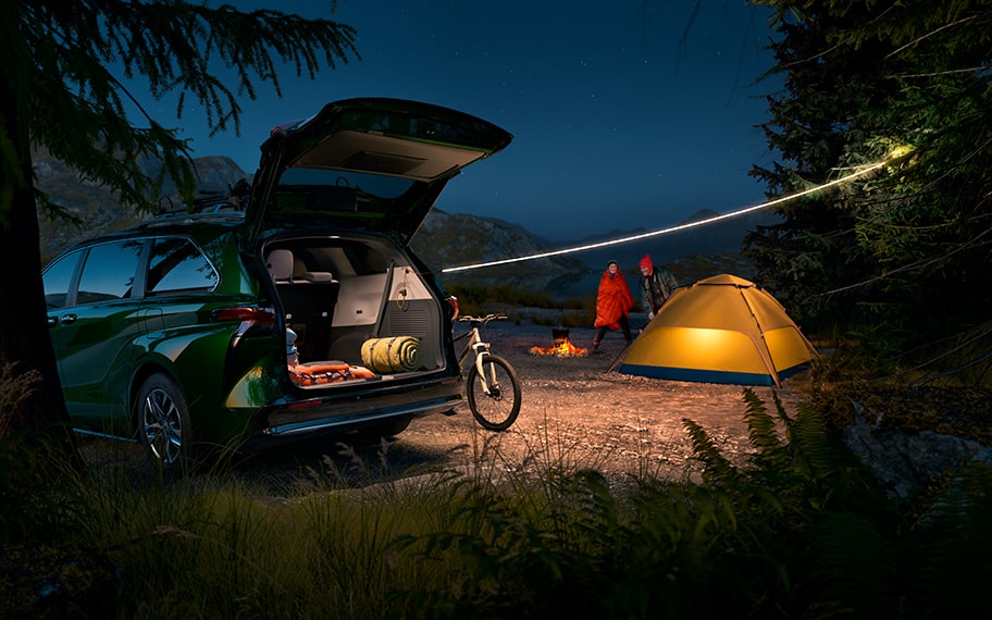 A Sienna is parked in front of a campsite at nighttime.