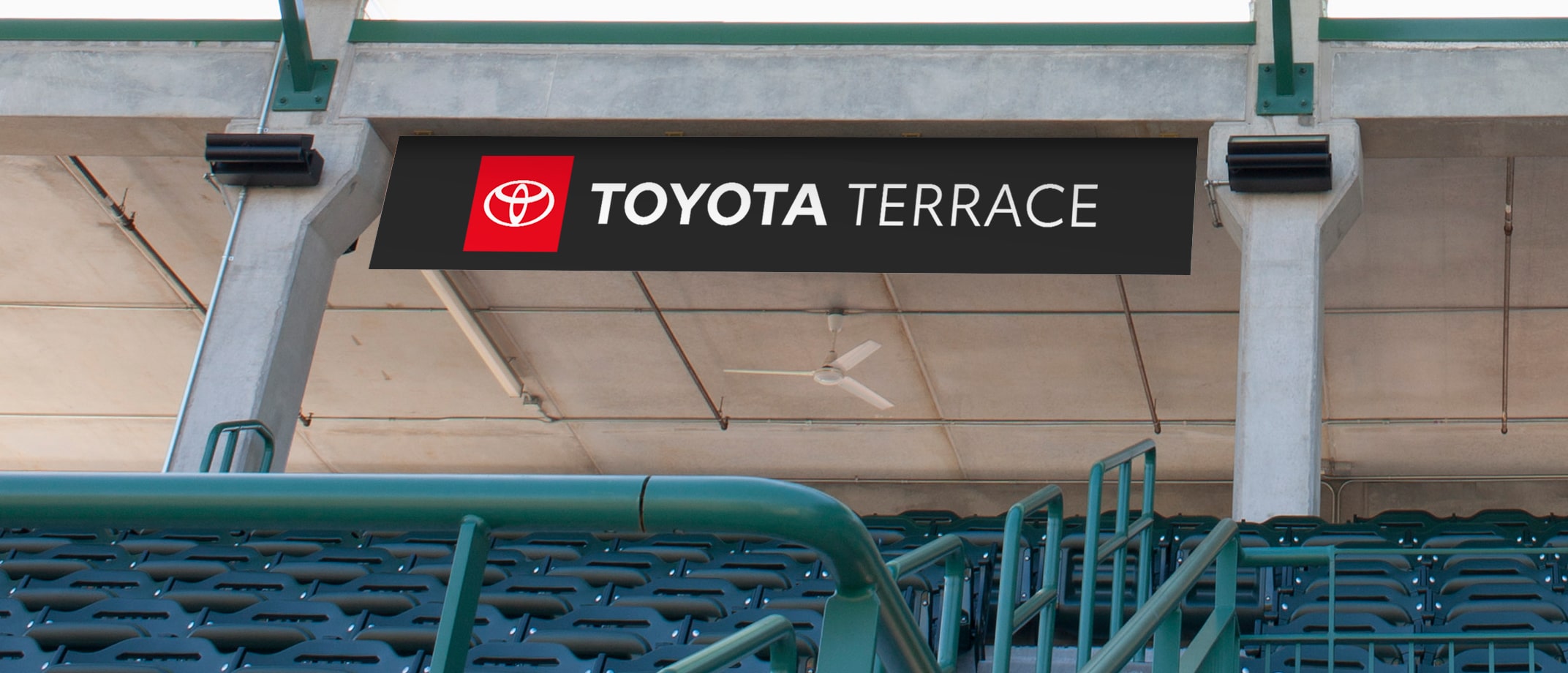 A range of Toyota Type signage examples including a soccer field with signage on the sides of the building, wall signage in a club bar, a signage banner hanging above stands in a  stadium, signage on the entry doors of a large building.