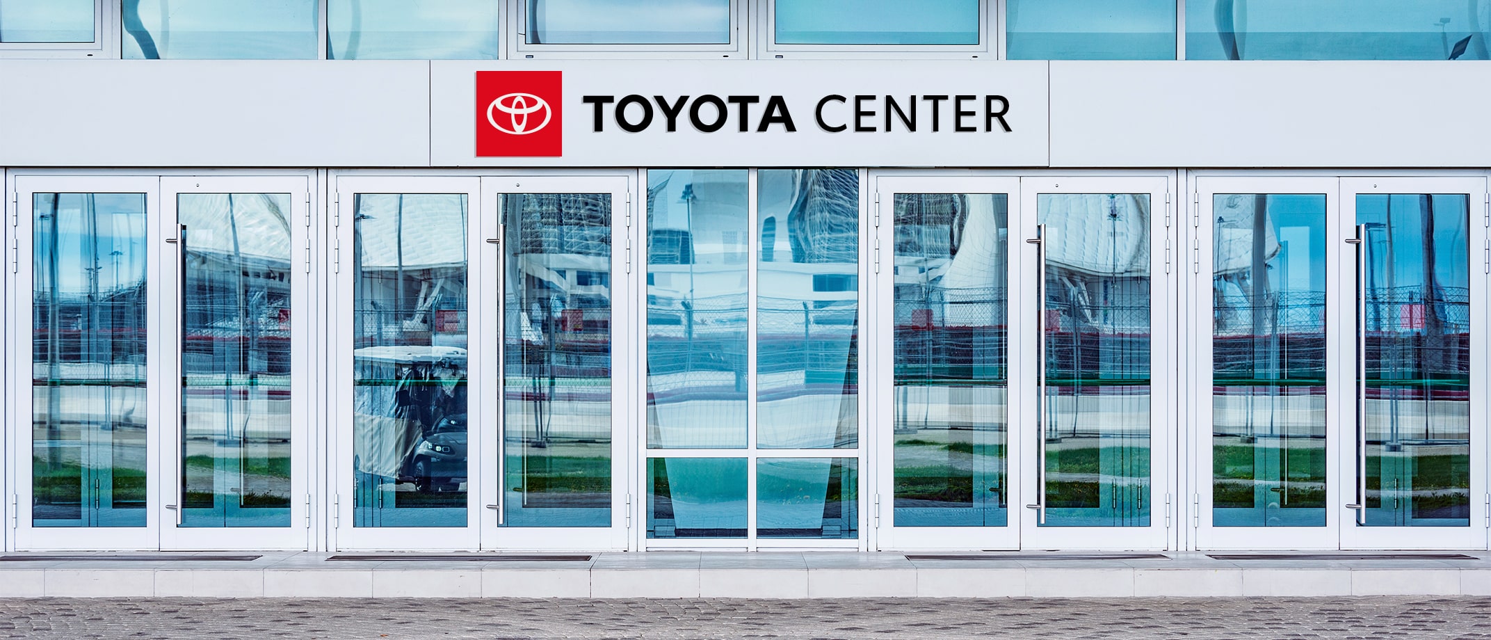 A range of Toyota Type signage examples including a soccer field with signage on the sides of the building, wall signage in a club bar, a signage banner hanging above stands in a  stadium, signage on the entry doors of a large building.