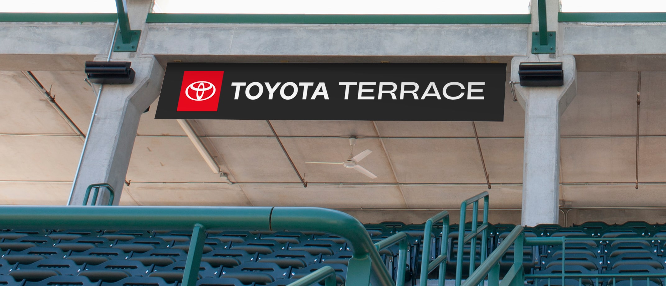 A range of Toyota Type signage examples including a soccer field with signage on the sides of the building, wall signage in a club bar, a signage banner hanging above stands in a  stadium, signage on the entry doors of a large building.