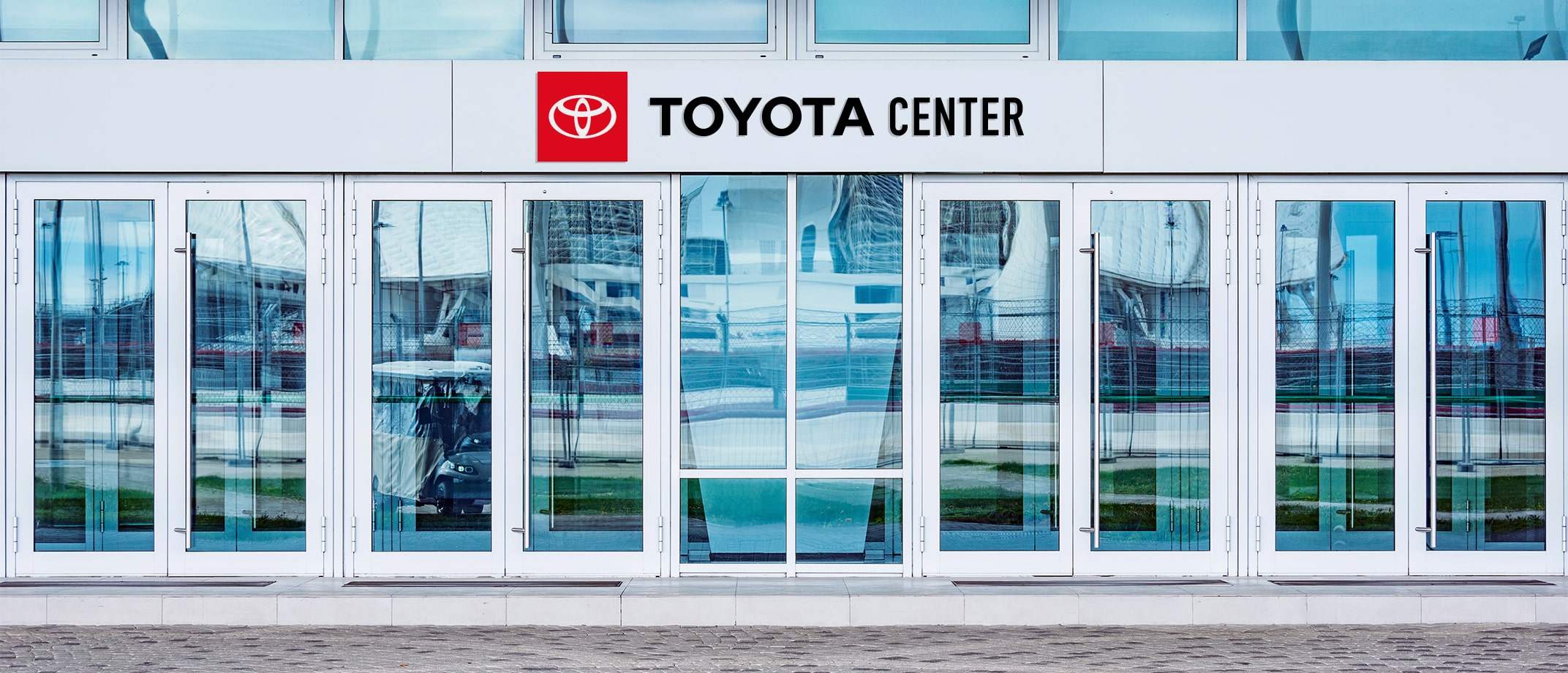 A range of Toyota Type signage examples including a soccer field with signage on the sides of the building, wall signage in a club bar, a signage banner hanging above stands in a  stadium, signage on the entry doors of a large building.