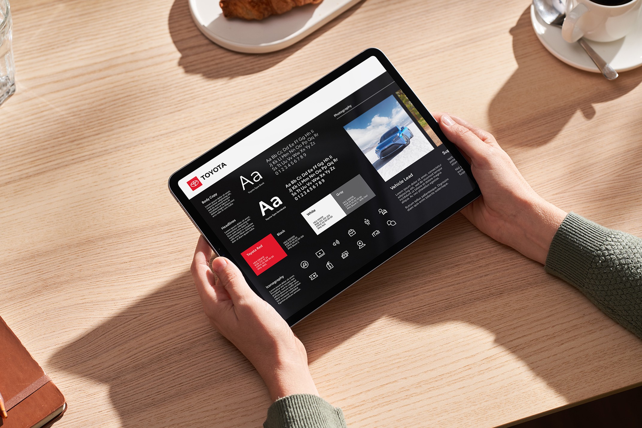 An overhead shot of a person holding an iPad, looking at information about typography, layout, and photography.
