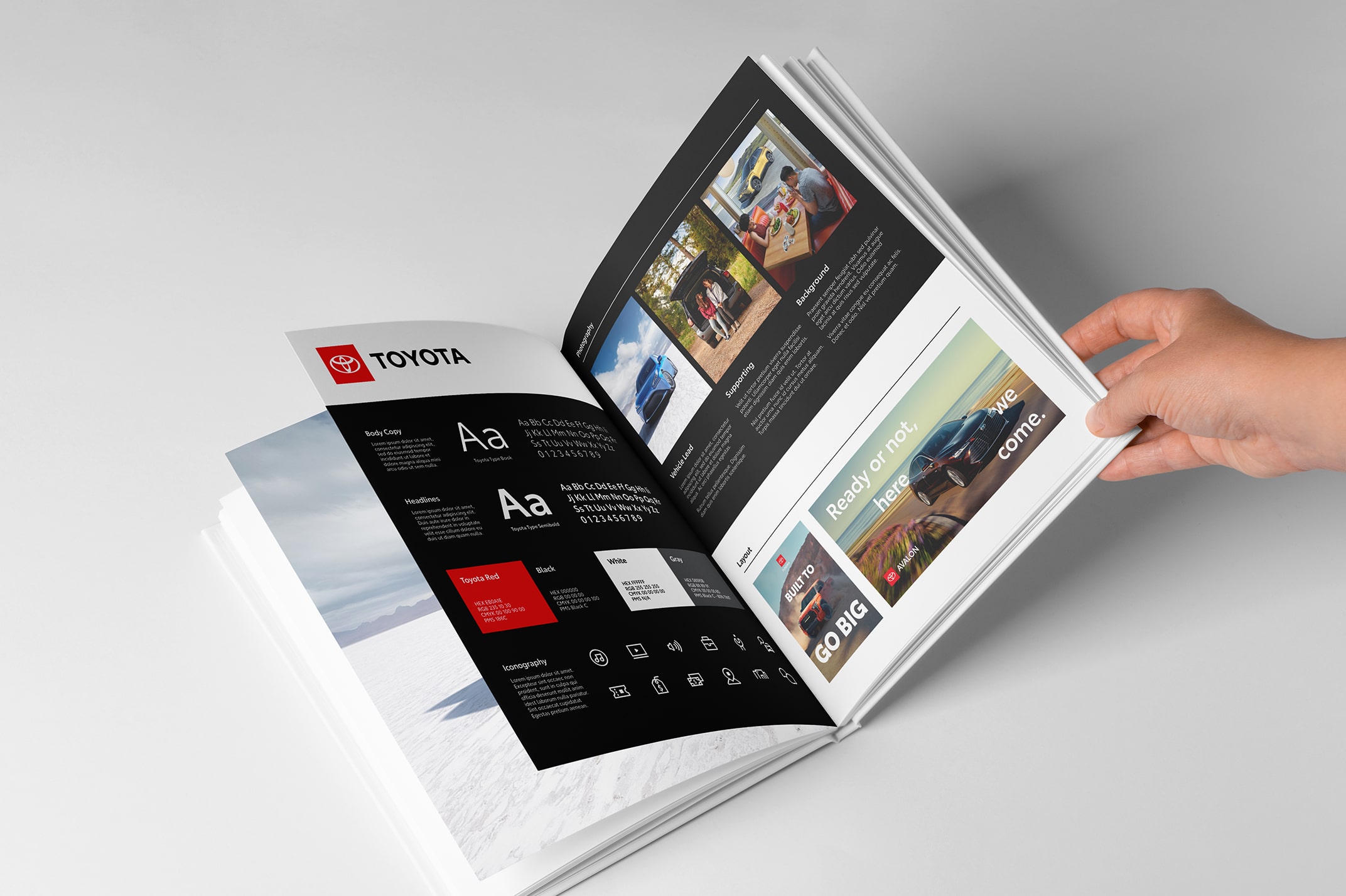 A hand flips through a Toyota Brand Handbook with pages about typography, layout and photography.