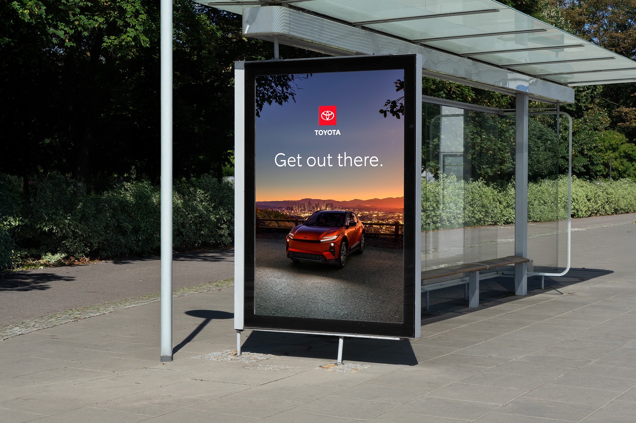 A bus sign displayed in a neighborhood features an image of a vehicle overlooking the city. The headline reads “Get out there.