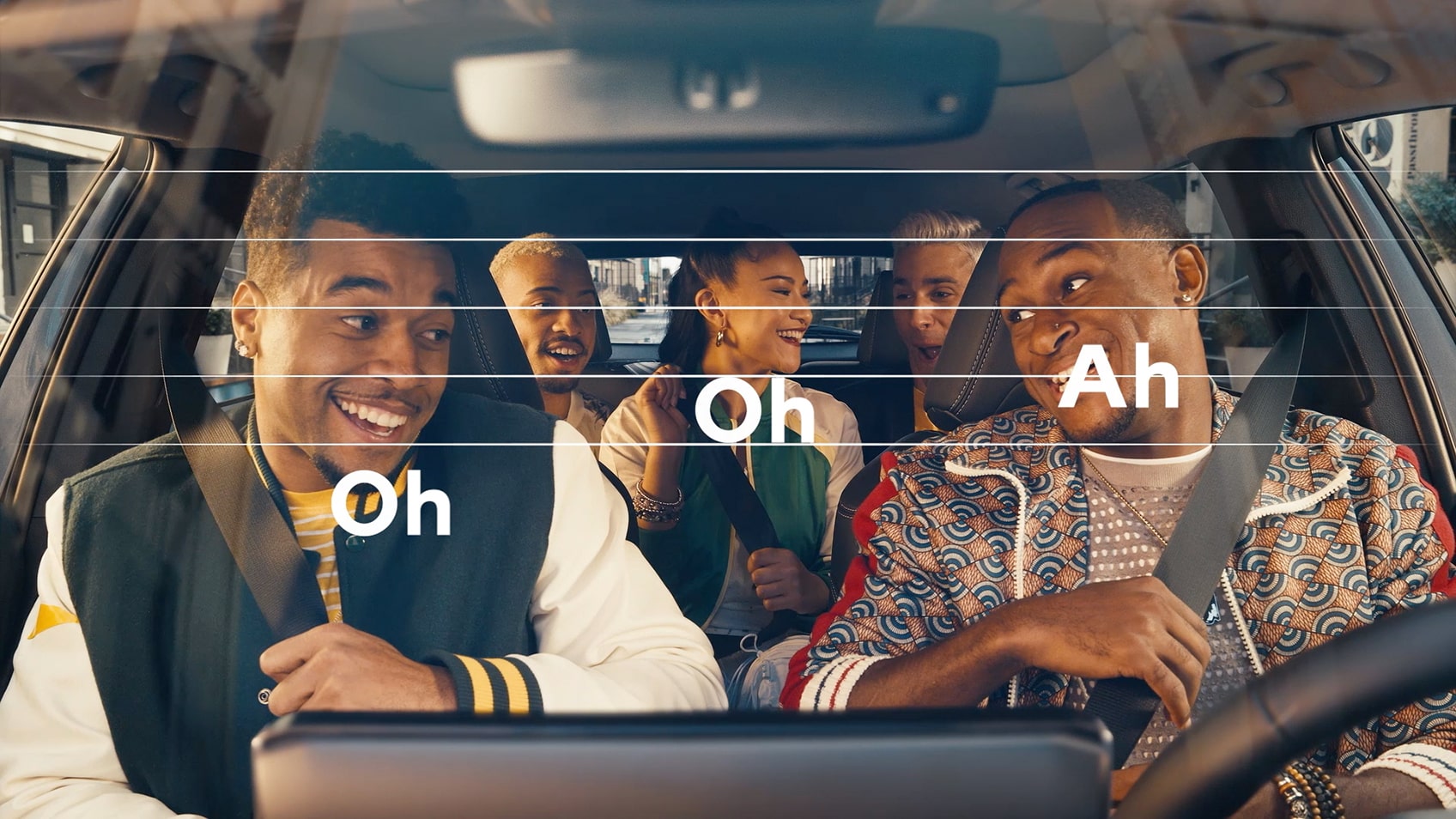 An image of friends inside a vehicle singing along to music with a super of the words “Oh Oh Ah” displayed like musical notes.