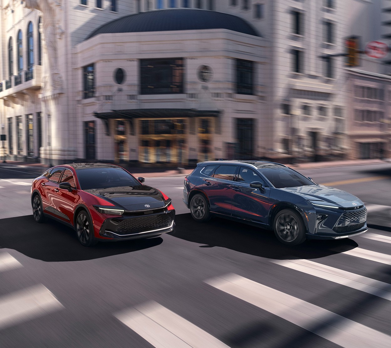 Two Toyota vehicles driving down the street with a blurred out white city building in the background