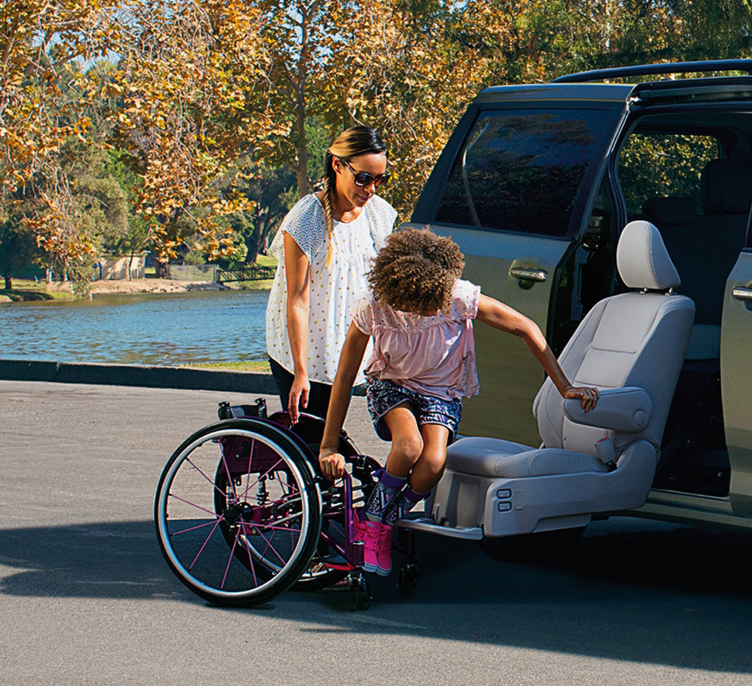 A mom assists her daughter as she gets out of a Toyota vehicle and into her wheelchair.